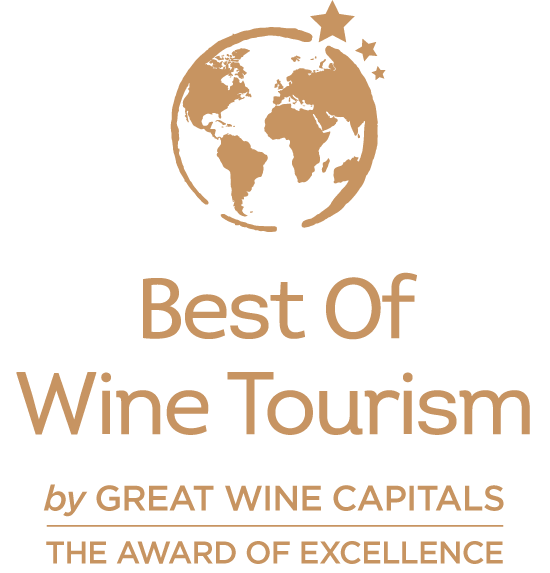 Best Of Wine Tourism Goldfarbenes Logo auf schwarzem Hintergrund mit stilisierter Weltkugel und Sternen. Darunter stehen die Texte „Best Of Wine Tourism“, „by Great Wine Capitals“ und „The Award of Excellence“.